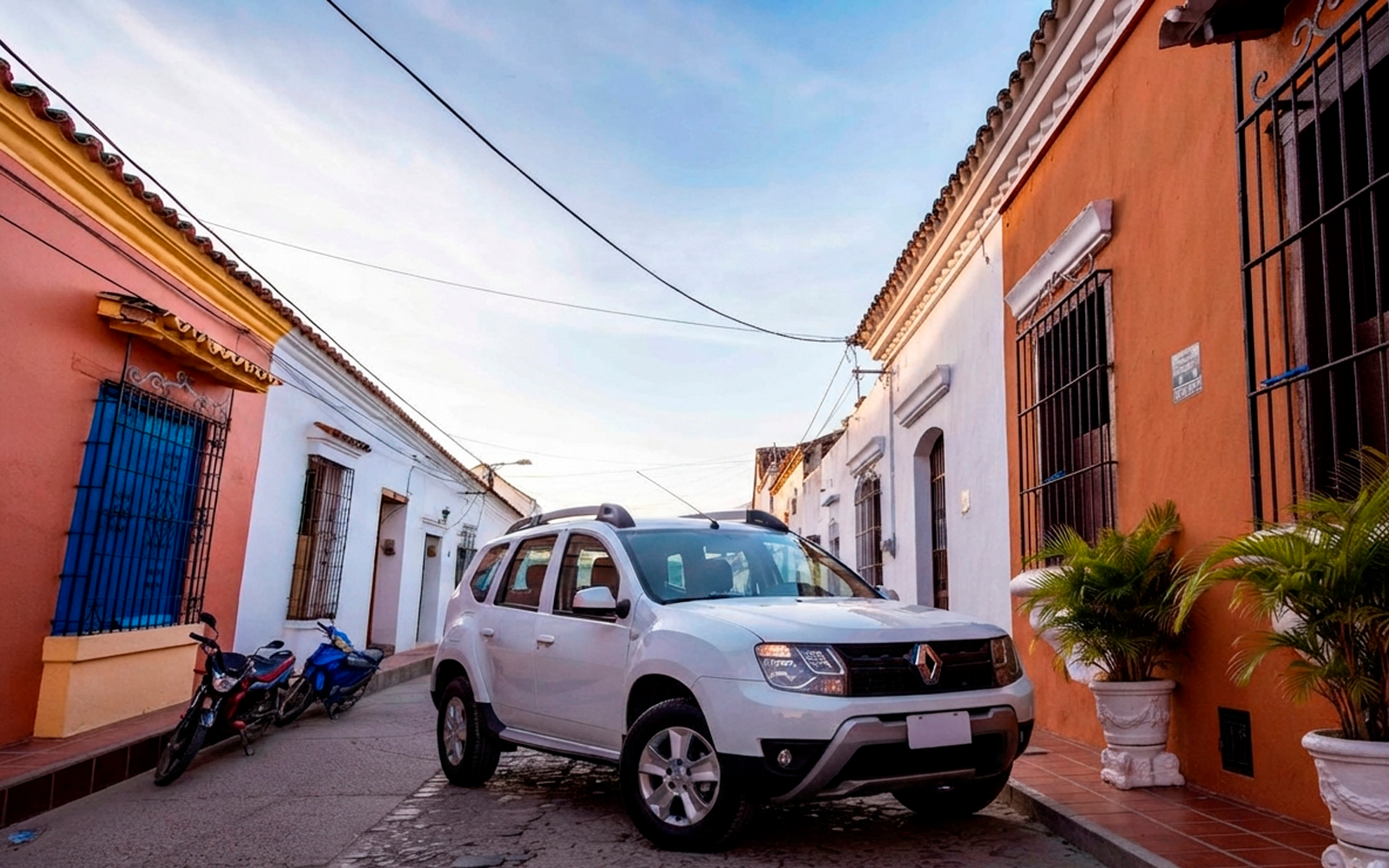 Camioneta blanca de transporte privado en una calle empedrada de casas coloniales de Mompox